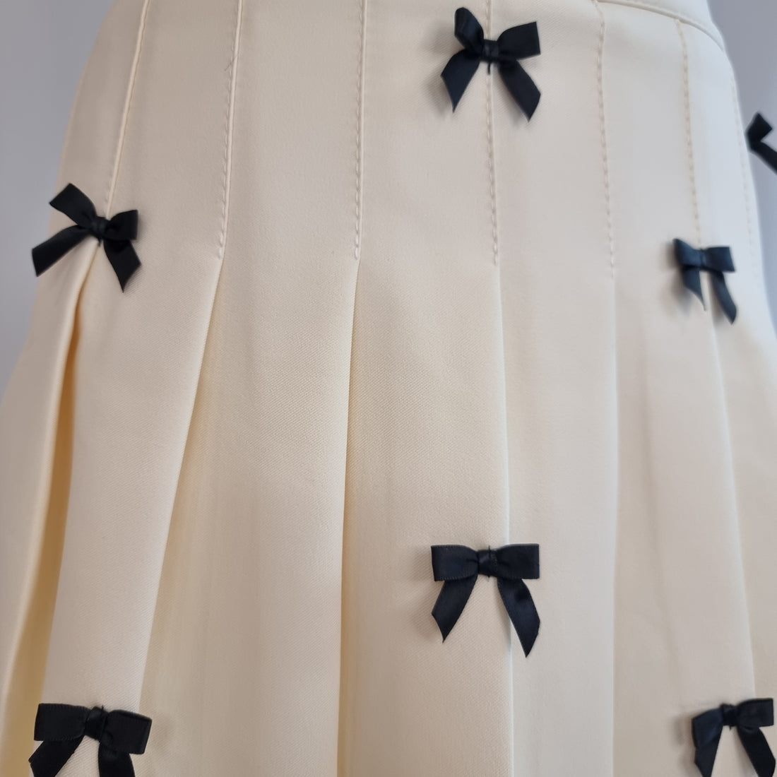 Cream Pleated Mini Skirt with Black Bow Accents